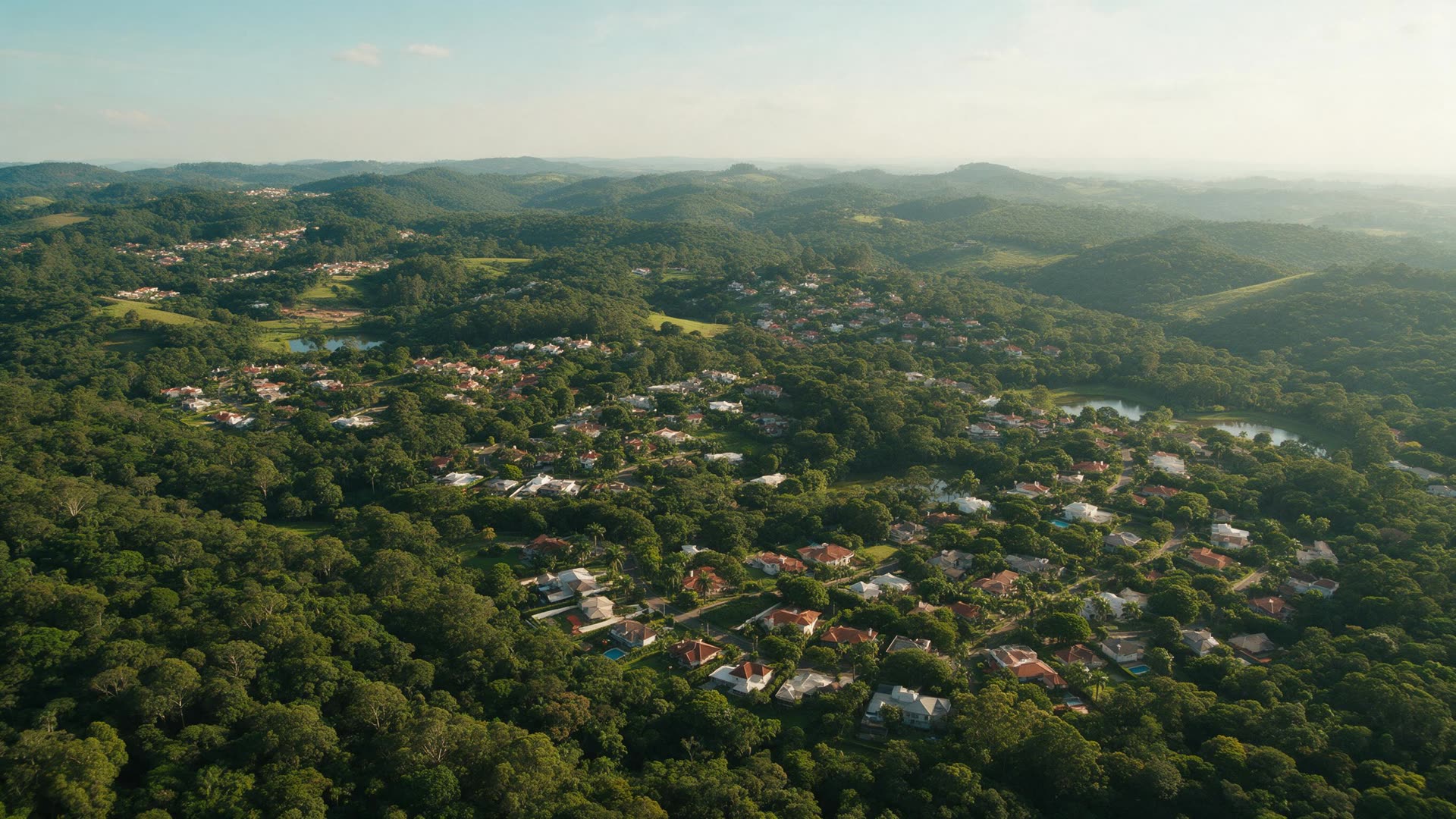 Vista aérea da região da Granja Viana ao entardecer, com mata preservada e residências entre as árvores